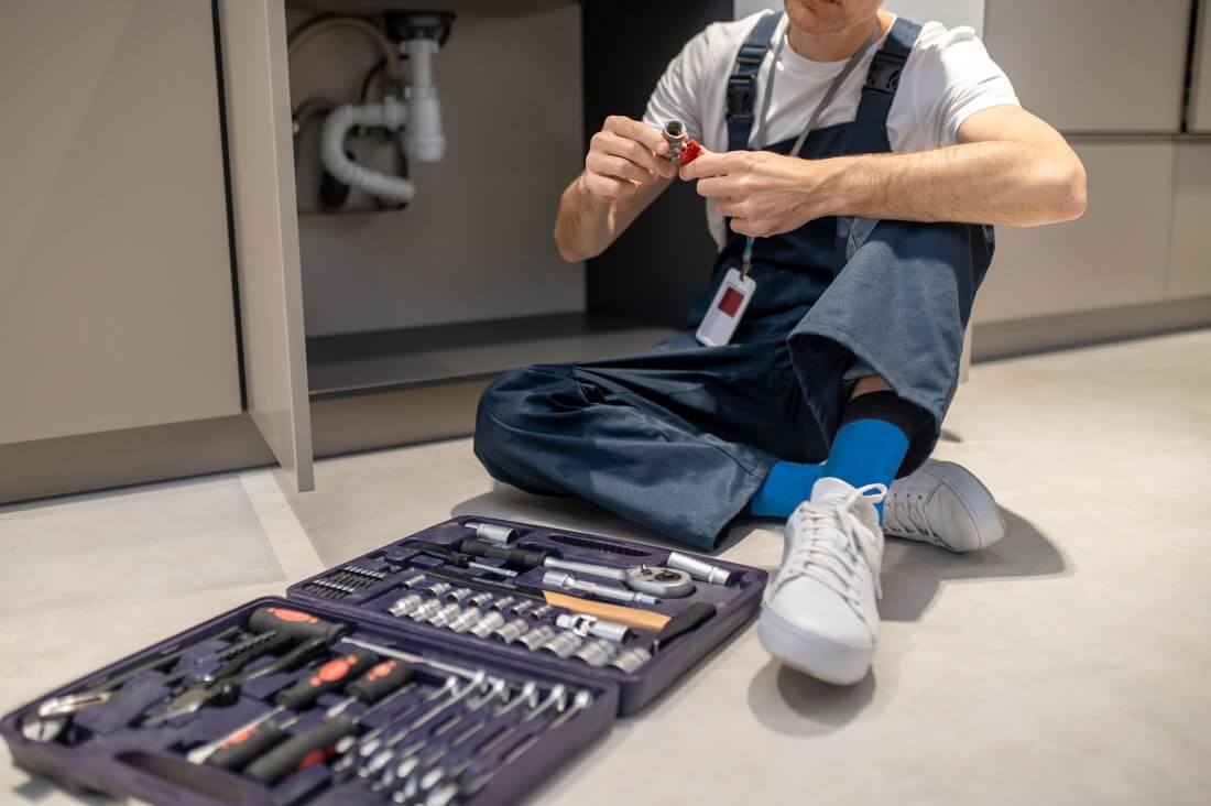 man sitting on floor with plumbing detail in hands